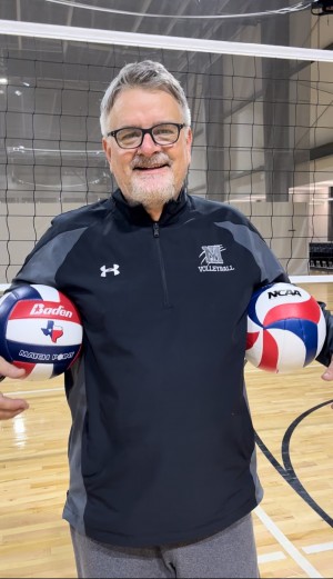James Seidel in an indoor volleyball court holding volleyballs