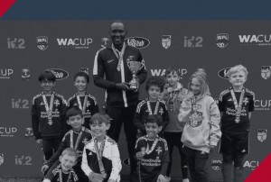 Group photo of a youth soccer team with a coach Gabriel Kalembo holding a trophy