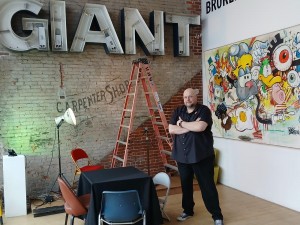 Brad stands in from of his 2021 Painting and our in progress signage