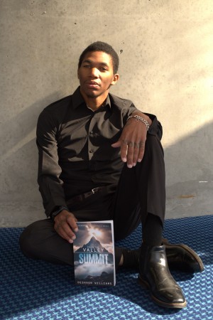 Williams poses as he holds the corner of his book “From The Valley to the Summit”