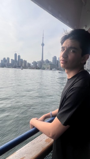 Sani on the a ferry, wearing the official school wristband, designed by him and sold by the school
