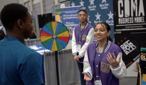Crowd gathers at CDMA Business Model Academy exhibit table, Walter E. Washington Convention 