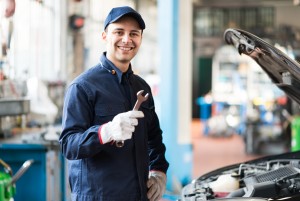 portrait smiling mechanic holding wrench his garage