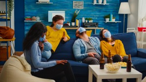 group multi ethnic friends watching comedy show tv laughing wearing face mask prevent infection with
