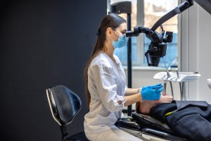 young female dentist treating patients teeth with dental microscope dentistry concept
