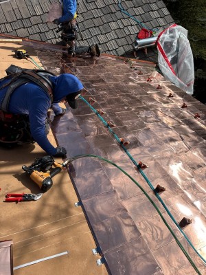 Copper roof getting RG10 copper snow guards installed by Umbrella Roofing team member. 