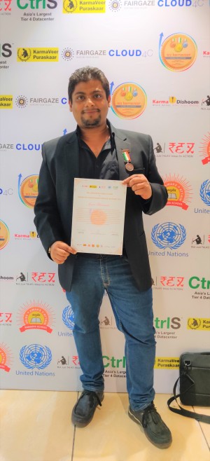 Fernandes standing in front of the United Nations/Karamveer Chakra logo