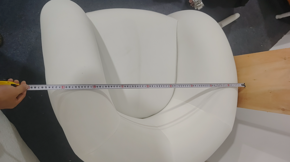 A tape measure is used to check the width of an upholstered lounge chair ALT A tape measure stretc
