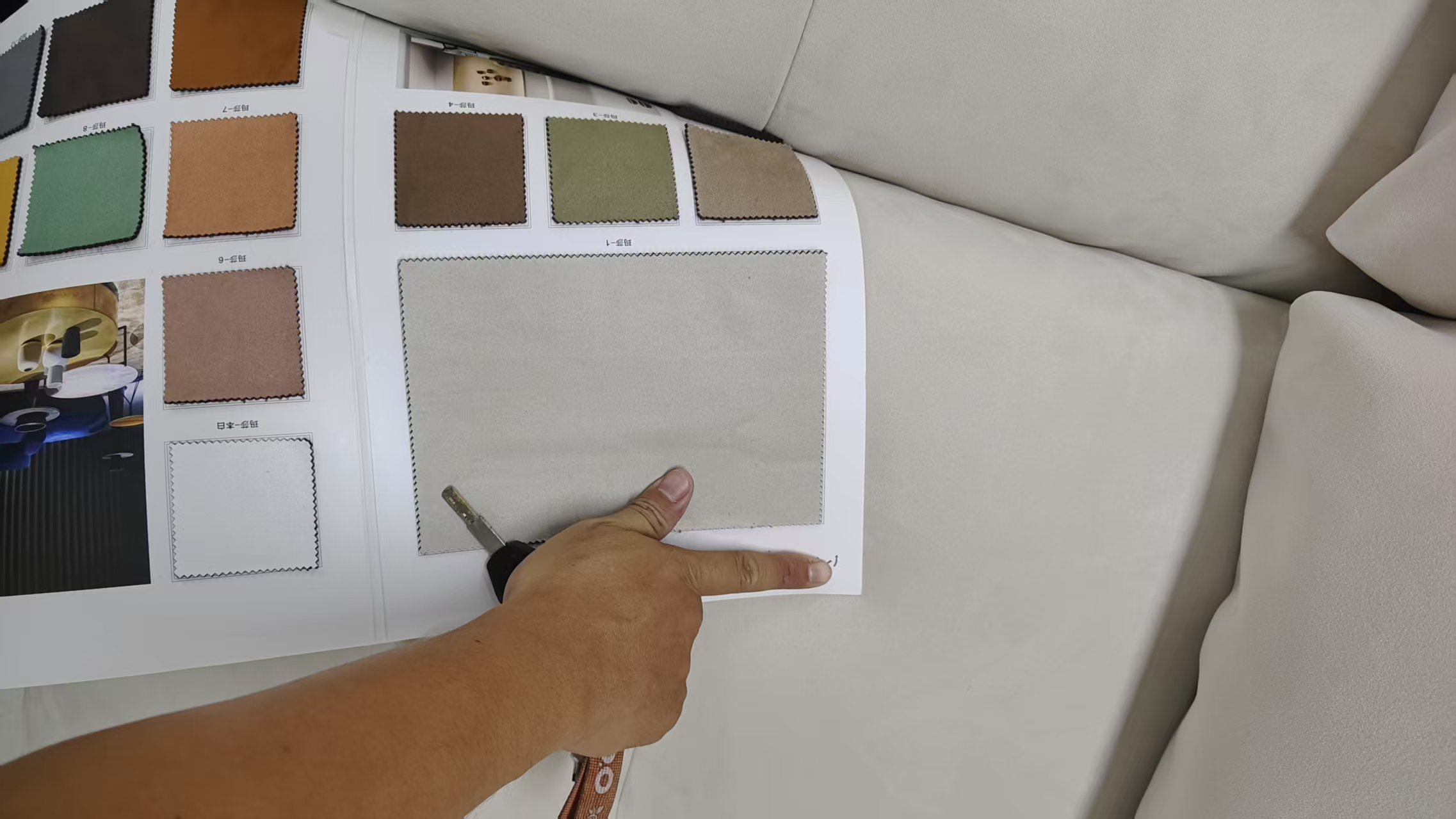An upholstery swatch is compared with a sofa surface to check color and texture consistency