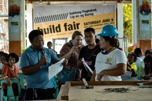 A trainer (left) provided guidelines on how to properly use construction tools in building a house.