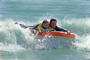 Mom helps her daughter catch her first wave