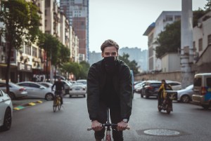 Male wearing scarf biking in the city streets