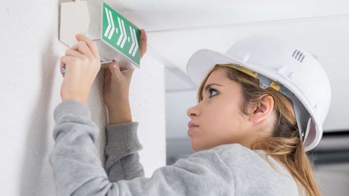 Careers Page Sign, Billboard, and Display Background Image A Sign, Billboard, and Display worker installs a sign in a hallway