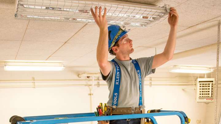 Careers Page Sign, Billboard, and Display Background Image A Sign, Billboard, and Display worker installs a sign in a hallway