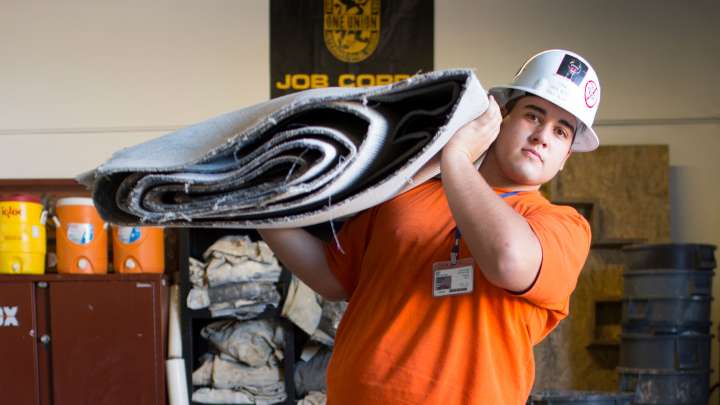 Careers Page Sign, Billboard, and Display Background Image A Sign, Billboard, and Display worker installs a sign in a hallway