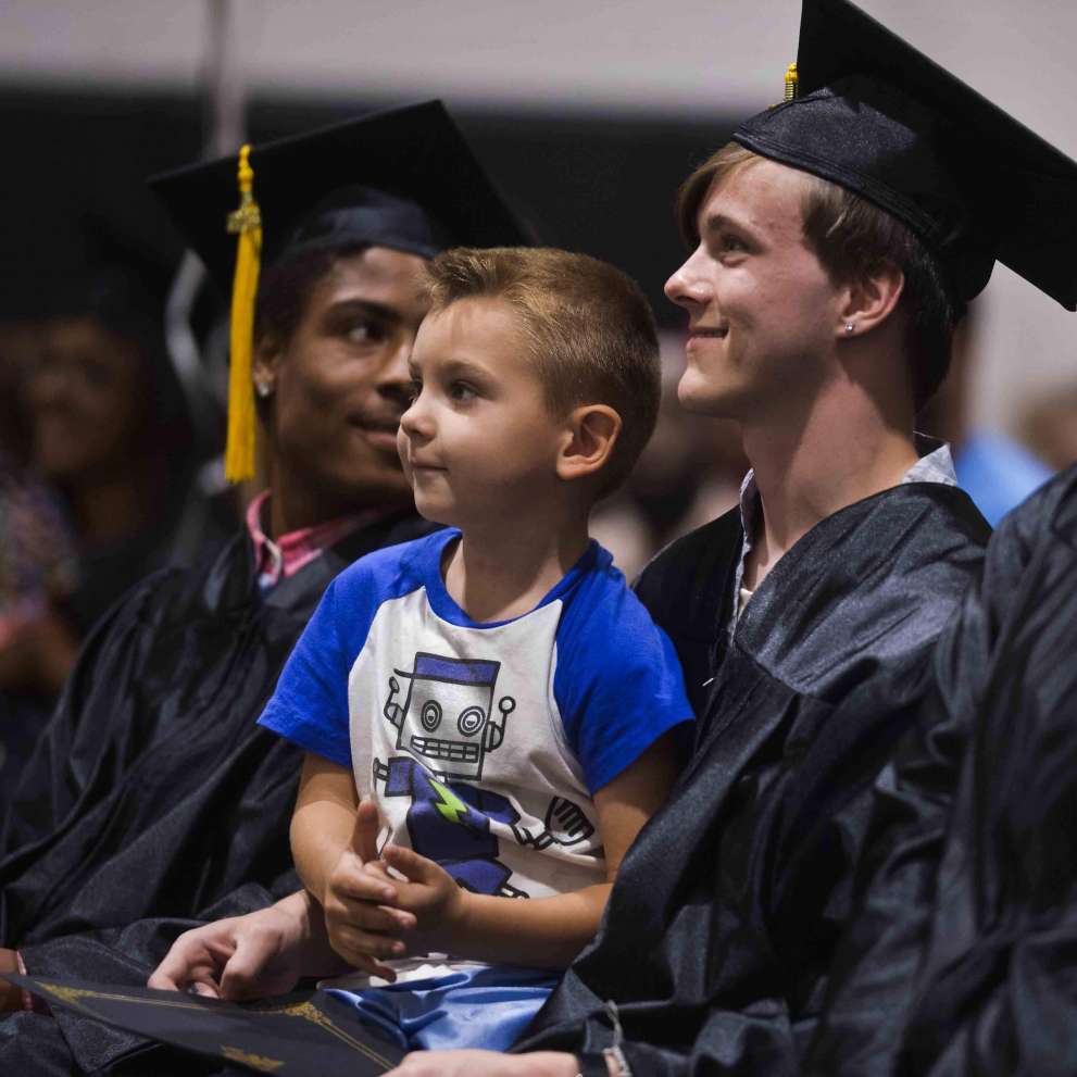 For Citizens Page Background Image A proud graduating student holds his son in his lap.
