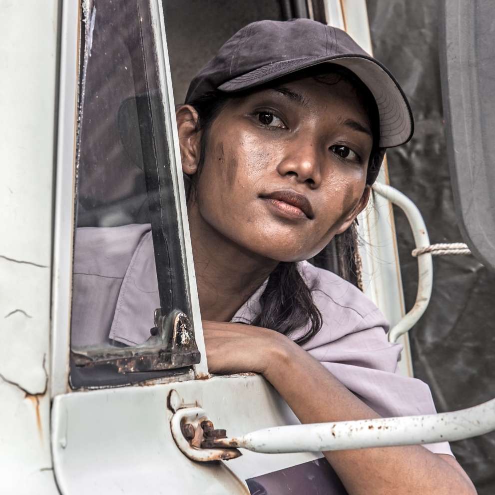 Careers Page Heavy Truck Driving Background Image A Heavy Truck Driving woman looks at the road ahead of her