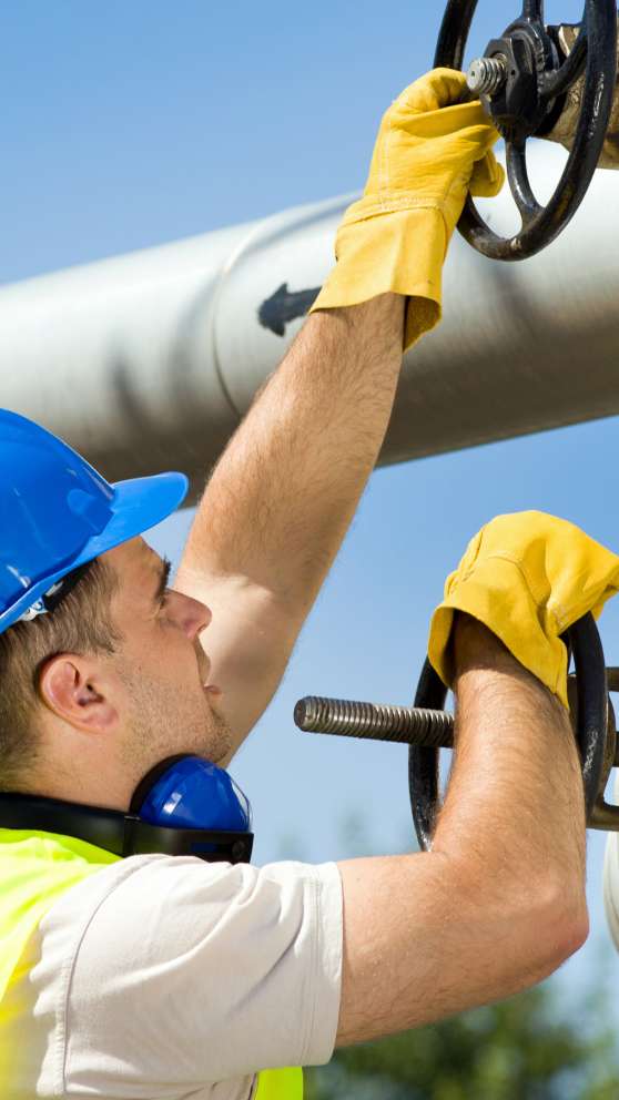 Careers Page Roustabout Operator Background Image A Roustabout Operator turns a valve wheel at a refinery