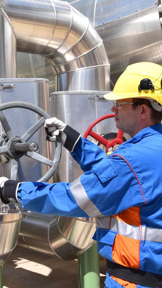 Careers Page Stationary Engineer Background Image A Stationary Engineer turns a valve wheel at a plant.