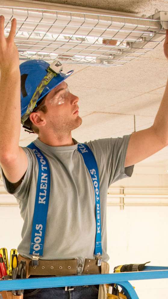 Careers Page Sign, Billboard, and Display Background Image A Sign, Billboard, and Display worker installs a sign in a hallway