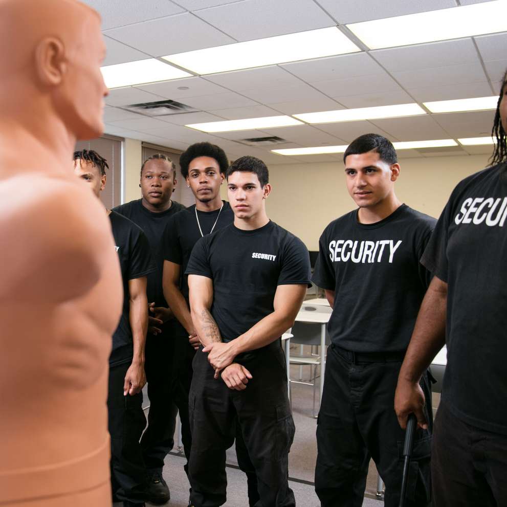 Advanced Security & Protective Services career image Security students in class with instructor and security dummy