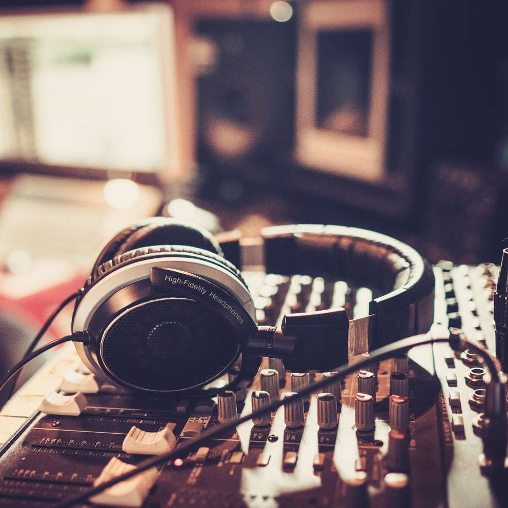 A pair of headphones rests on a soundboard
