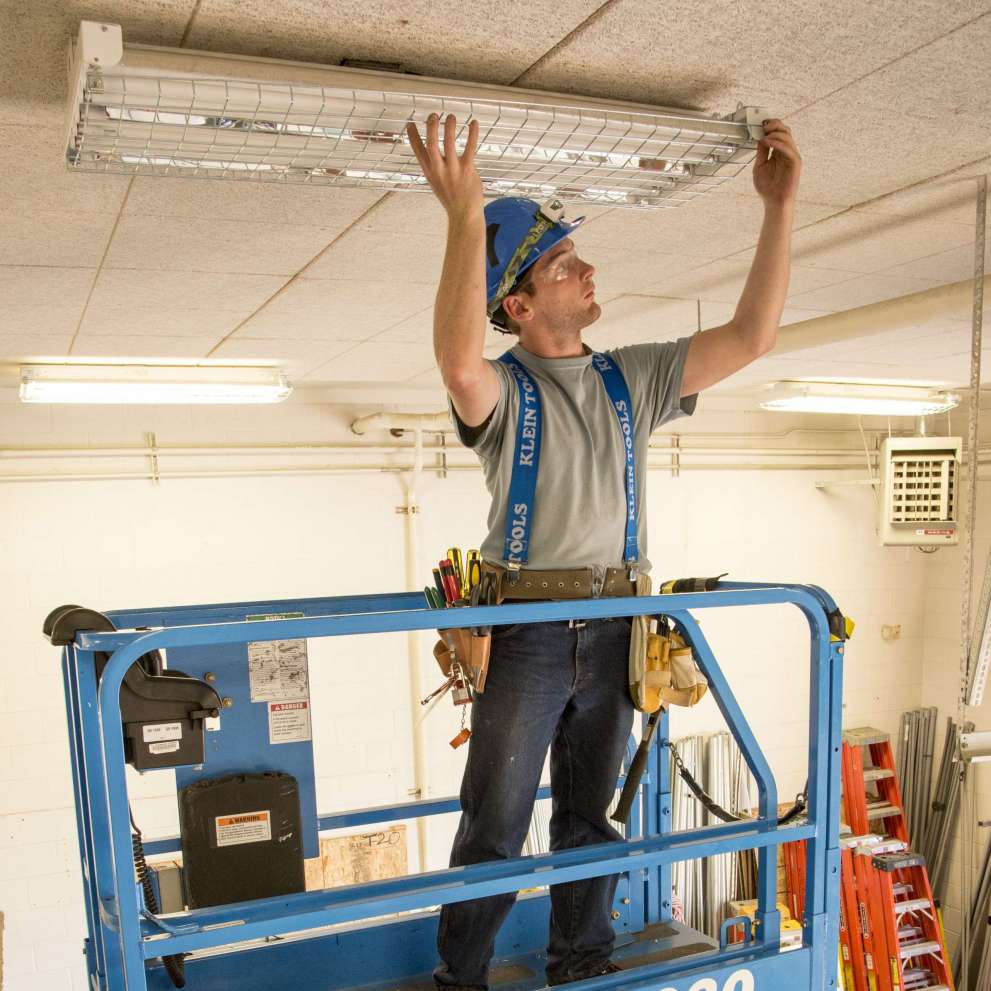 Careers Page Sign, Billboard, and Display Background Image A Sign, Billboard, and Display worker installs a sign in a hallway