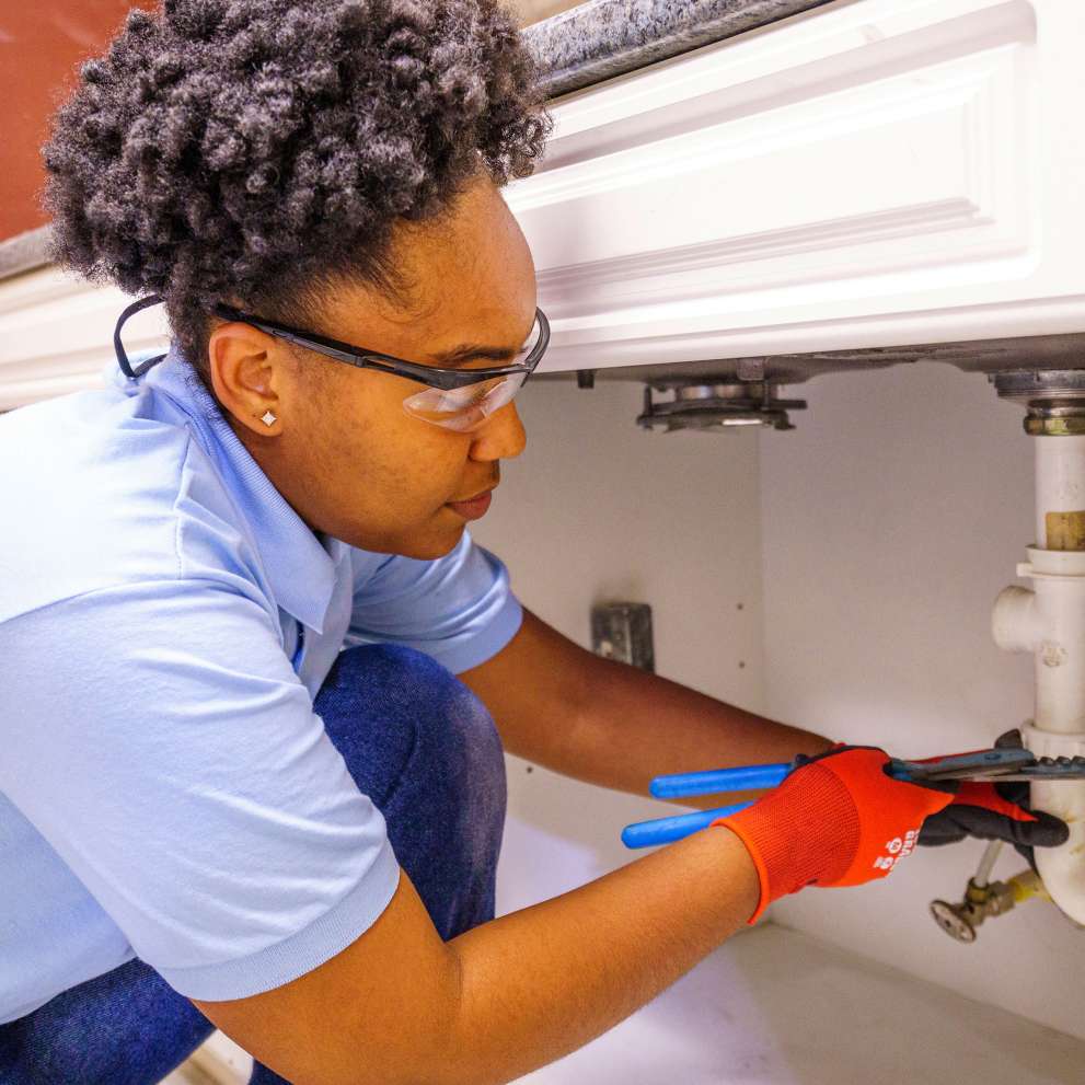 A Job Corps student performs a plumbing repair