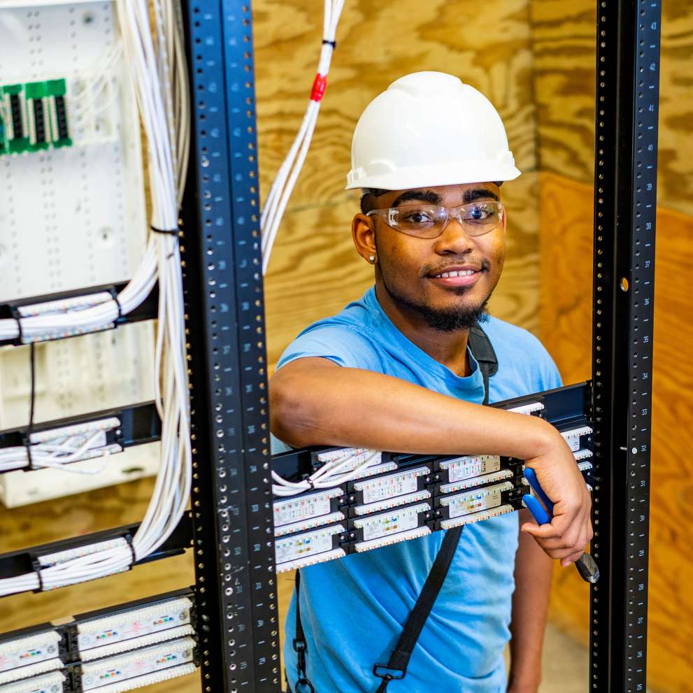 A network cable installation technician arranges telecommunications cables