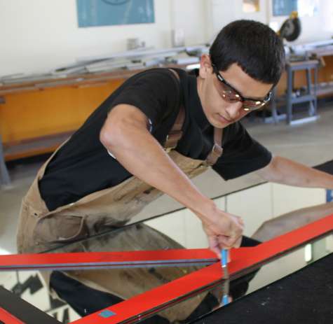 A glazier cuts a piece of glass.