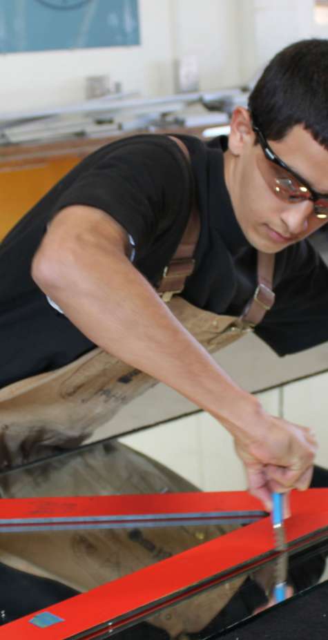 A glazier cuts a piece of glass.