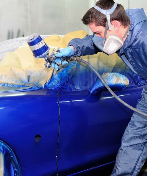 A Collision Repair and Refinish student paints a car blue. 