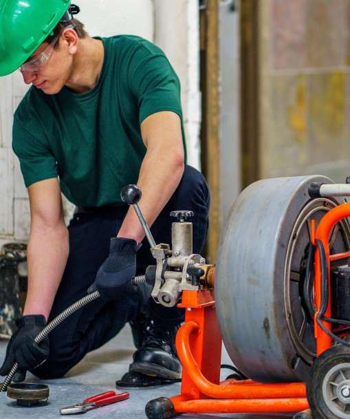 A plumber uses a drain-cleaning machine.