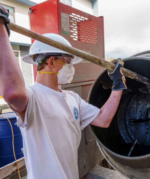 A cement masonry worker mixes a batch of cement.