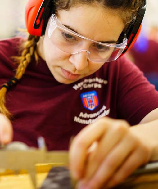 A manufacturing technician takes a measurement with caliper. 