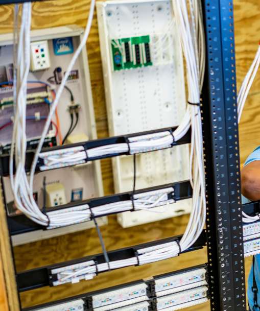 A network cable installation technician arranges telecommunications cables