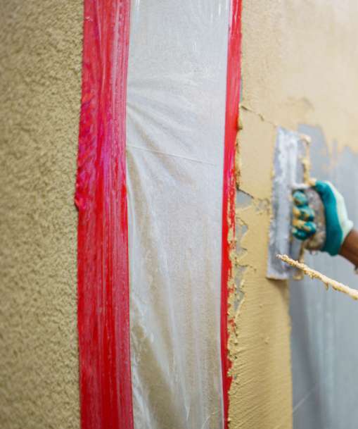 A plastering technician applies a coat to a wall.