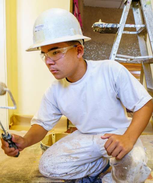 A painter works on an interior wall.