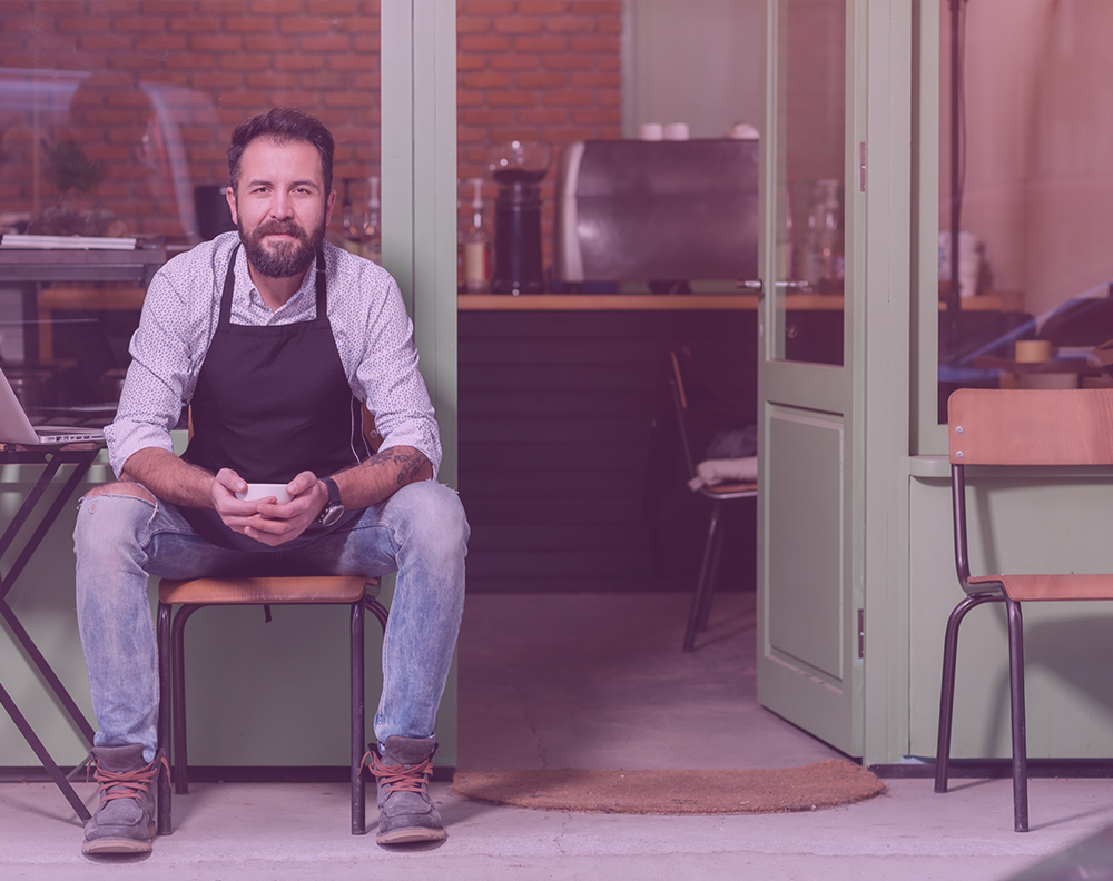 Emprendedor afuera de su cafetería pensando en mejorar su historial de crédito