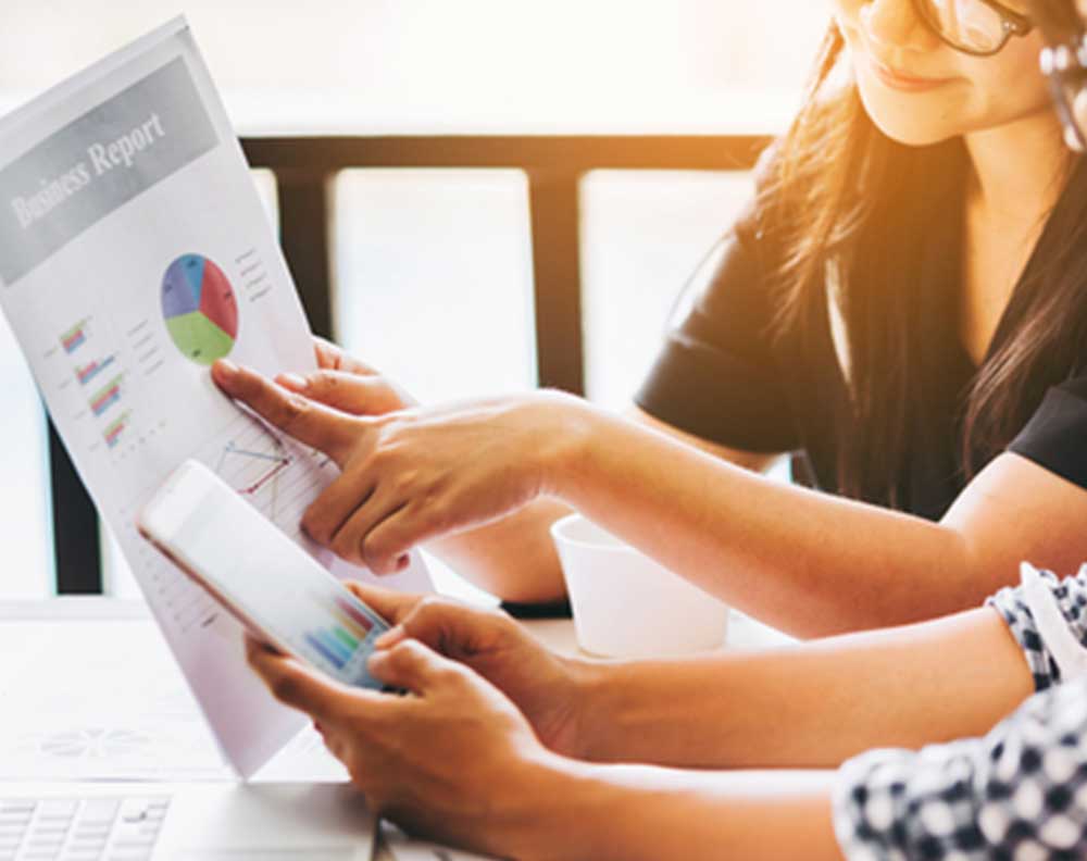 Dos mujeres jóvenes revisando la salud financiera de su negocio con una aplicación móvil