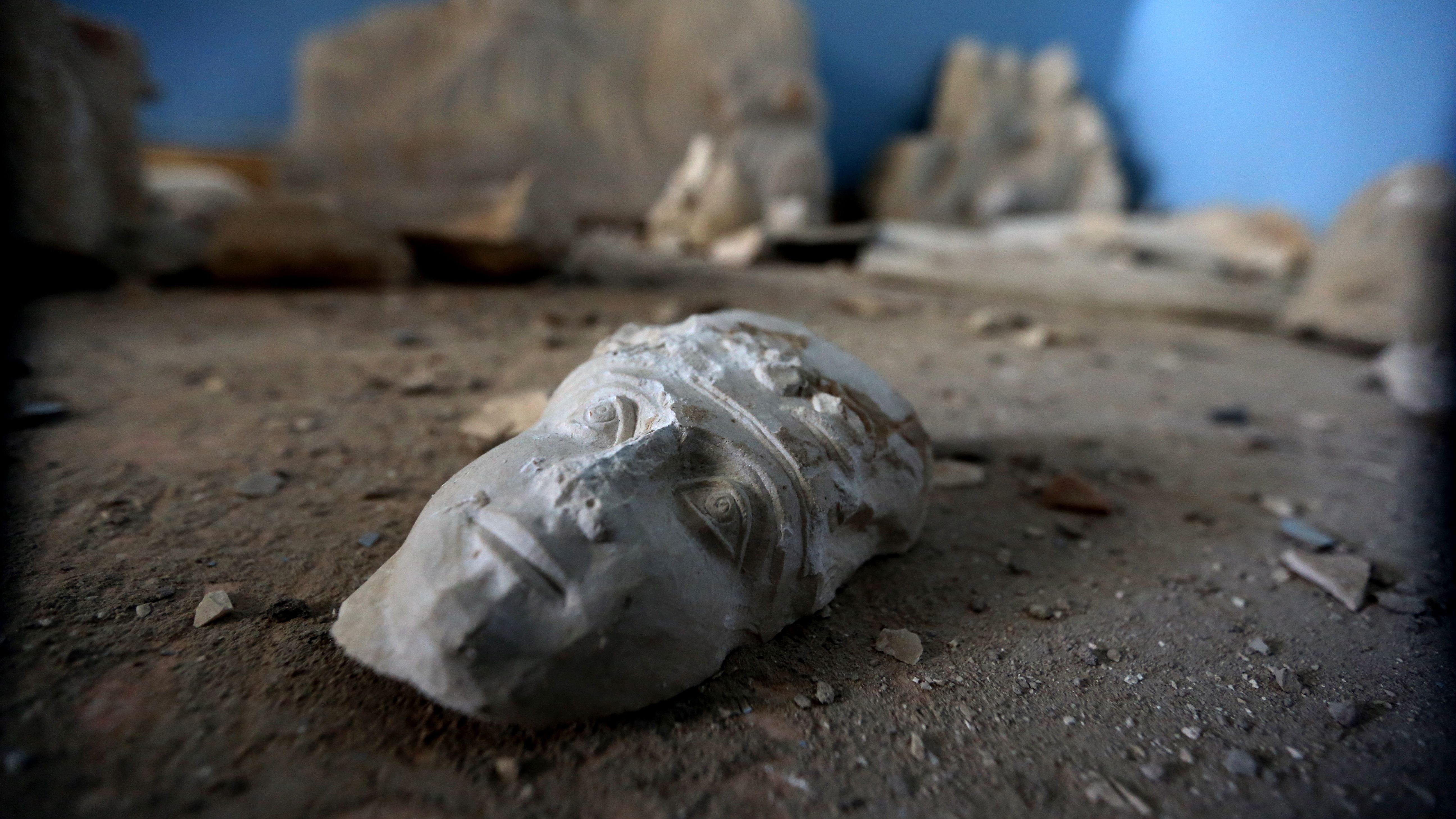 The face of a statue lies on the ground at the destroyed museum in the