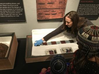 An employee of the Alutiiq Museum and Archeological Repository in Kodiak displays a beaded dance belt and cuffs, part of the Pinart Collection on loan from the Museum Bologne-Sur-Mer on Monday, July 9, 2018. (Photo by Daysha Eaton/KMXT)