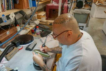 Anthony Garcia engraves a silver bracelet in the hobby shop at Spring Creek Correctional Center. (Photo by Hillman/Alaska Public Media)