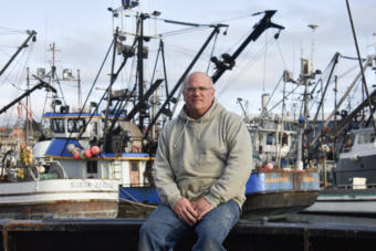 Cod fisherman Frank Miles sits on the deck of the Sumner Strait, docked in Kodiak’s St. Paul Harbor. (Photo by Kavitha George/Alaska’s Energy Desk)