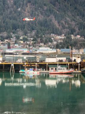 A Coast Guard Jayhawk helicopter flies over Gastineau Channel in Juneau as authorities investigate a pleasurecraft that had been reported unmanned and adrift with its motor running on Friday, Nov. 29, 2019. The Coast Guard later reached the vessel's owner and someone entrusted to move it and called off the search.