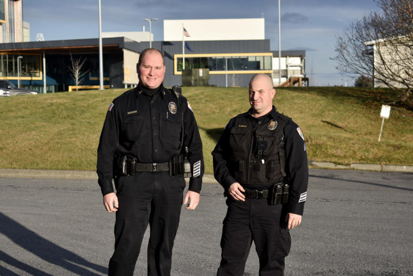 Two police officers pose outside for a photo.