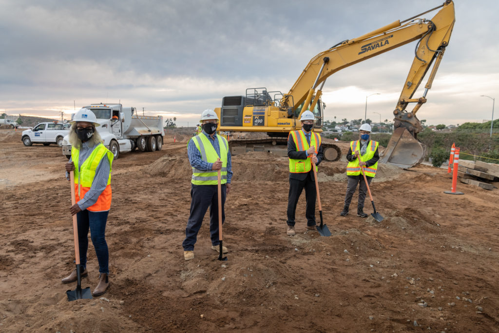 4 people socially distanced at construction site with shovels