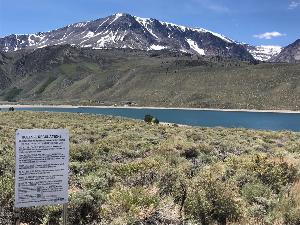 Image of a lake snowcapped mountains and a sign that reads rules and regulations