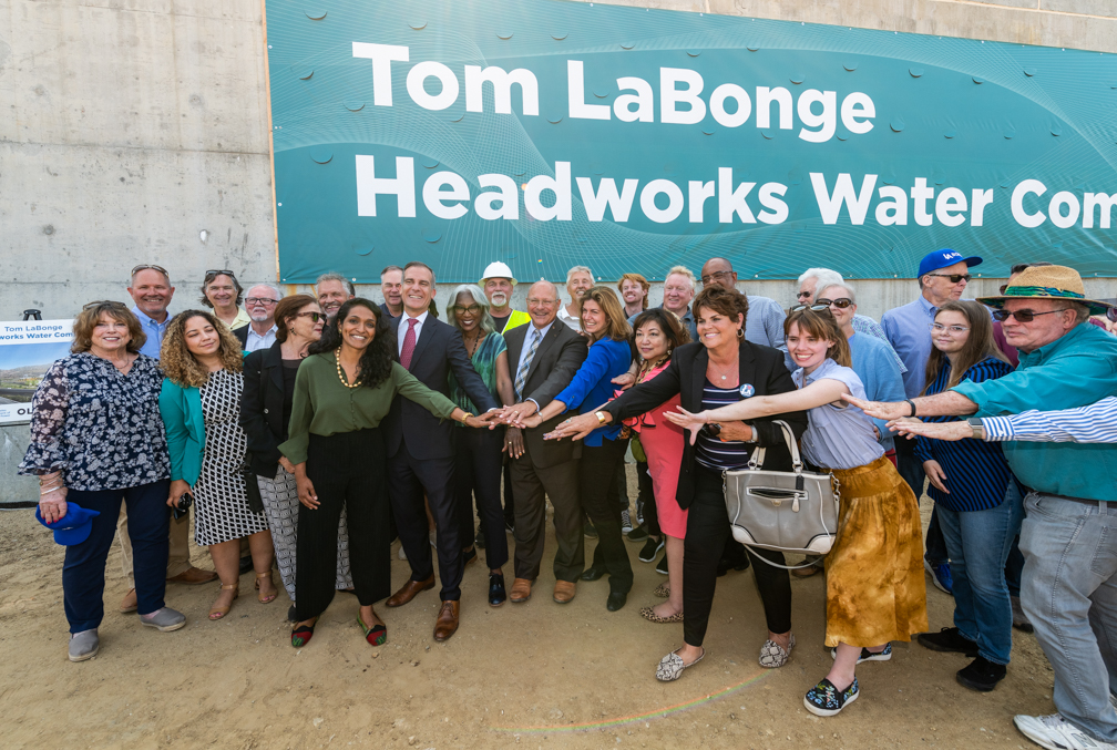 Image of a group of people in front of a large banner that reads tom labonge headworks water complex