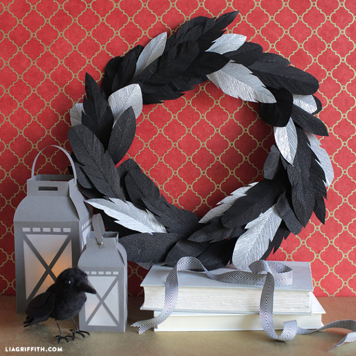 crepe paper crow feather wreath for Halloween next to lanterns and books